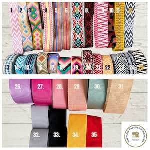 May include: A variety of colorful woven and solid-color straps, numbered 1-35, displayed on a light wood surface. The straps feature various patterns, including zigzags, geometric designs, and solid colors. The image includes a logo in the bottom right corner.