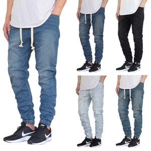 May include: Five different pairs of jeans with a drawstring waist and cuffed ankles. The jeans are in various shades of blue, black, and light blue. The jeans are paired with black sneakers.