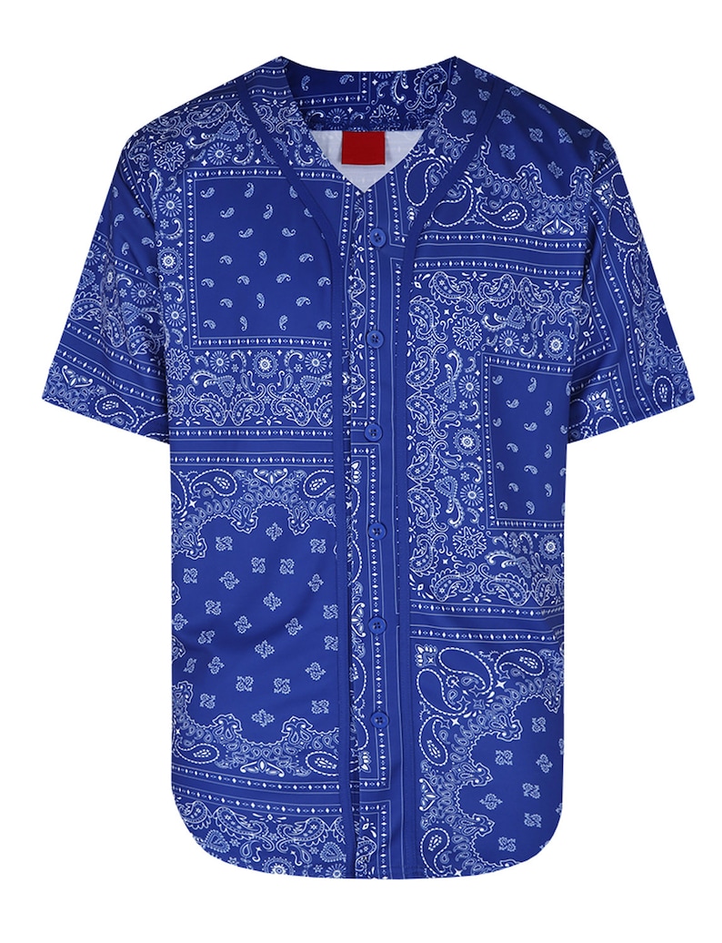 K&ouml;nnte beinhalten: Ein kurz&auml;rmeliges Baseball-Trikot in Blau mit wei&szlig;em Paisley-Muster. Das Trikot hat eine Knopfleiste und ein rotes Etikett am Kragen. Das Paisley-Muster ist in einem Patchwork-Stil angeordnet.