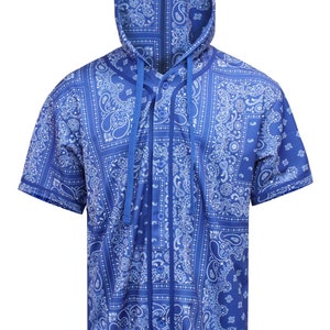 K&ouml;nnte beinhalten: Kurz&auml;rmeliges Hemd mit Kapuze und blauem Paisley-Muster. Das Hemd hat eine Knopfleiste und eine Kapuze mit Kordelzug. Der Stoff ist leuchtend blau mit einem wei&szlig;en Paisley-Design.