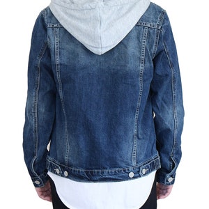 Pu&ograve; includere: Una giacca di jeans blu con una fodera con cappuccio grigia. La giacca ha una chiusura con bottoni e due tasche anteriori.