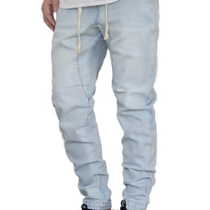 May include: Light blue denim pants with a drawstring waist and a relaxed fit. The pants are cuffed at the ankles and have a faded look.