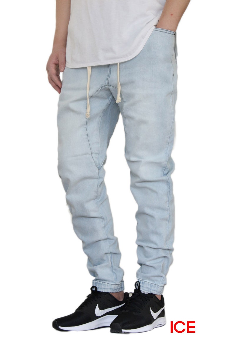 May include: Light blue denim pants with a drawstring waist and a relaxed fit. The pants are cuffed at the ankles and have a faded look.