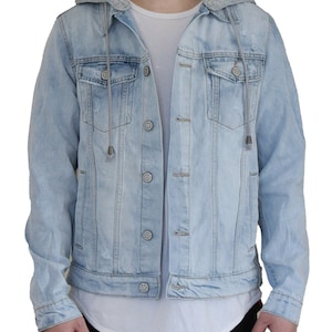 Pu&ograve; includere: Una giacca di jeans blu chiaro con fodera in cappuccio grigia. La giacca ha una chiusura con bottoni e due tasche anteriori.