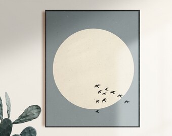 May include: A framed print with a minimalist design featuring a large off-white circle and a flock of black birds flying in formation against a light blue background.
