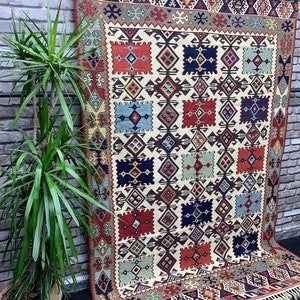 May include: A traditional rug with a geometric pattern in shades of red, blue, green, and white. The rug has a fringe border and is made of wool.