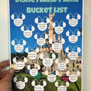 May include: A printable Disneyland Paris bucket list with a picture of Sleeping Beauty's castle in the background. The list includes activities like riding the carousel, taking a photo at the castle, watching fireworks, and going shopping in Disney Village.