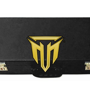 Puede incluir: Estuche rígido negro con un logotipo dorado de un "TM" estilizado dentro de un triángulo. El estuche tiene dos cierres y un asa.