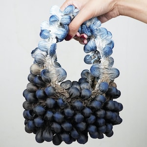 Può includere: Una scultura in ceramica blu e bianca con una forma organica unica. La scultura è composta da molte piccole forme arrotondate che sono raggruppate insieme.