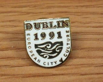May include: A gold-colored pin with a white background and the text "Dublin 1991 European City of Culture".