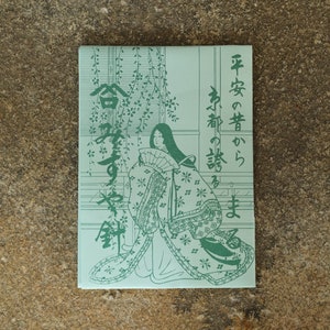 May include: A light green rectangular package featuring a Japanese illustration of a woman in traditional clothing. The illustration is in a detailed, line-art style. Japanese text is visible on the package.