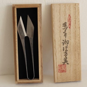 May include: A pair of silver scissors with a unique design, in a wooden box with Japanese writing on the lid. The writing reads "金寿堂"
