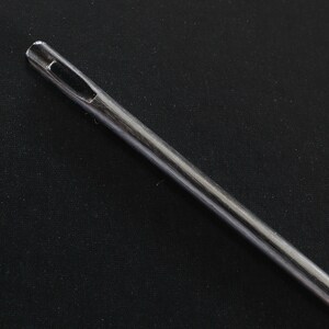 May include: A close-up of a silver sewing needle with a large eye.