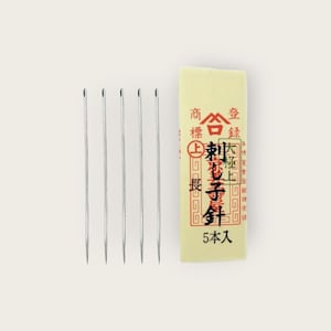 Könnte beinhalten: Eine Packung mit fünf silbernen Nähnadeln mit einem gelben und roten Etikett, auf dem "金  針  上  製  東  和  5 本 入" steht.