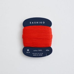May include: A spool of red cotton thread labelled "SASHIKO" with the text "cotton 100% 40m 20/4 daruma-ito.co.jp MADE IN JAPAN" on the label.