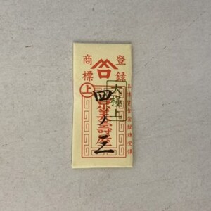 May include: A red and white paper envelope with Chinese characters that read "Shang Hai Jin", which translates to "Shanghai Gold". The envelope has a red border and a gold seal with a Chinese character.