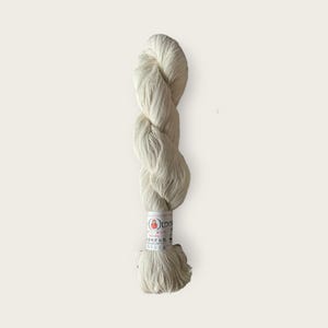 May include: A skein of white yarn with a label that reads "O.L.C.Y.A.  Handspun Cotton Yarn"