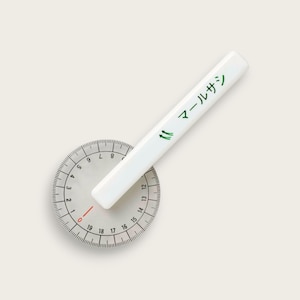 May include: A white protractor with a red line at zero degrees and black numbers from 0 to 19. A white ruler with the text "マールサシ" in green is placed on top of the protractor.