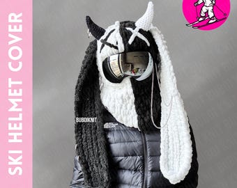 May include: Black and white ski helmet cover with a bunny design, horns, and goggles. The cover has long, floppy ears and a chain detail. The text "SKI HELMET COVER" is on the left side of the image.