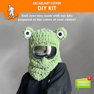 Könnte beinhalten: Ein grüner, gestrickter Skihelmbezug im Froschdesign, mit großen weißen und schwarzen Augen und einem reflektierenden Visier. Das DIY-Kit enthält Anleitungen zum Stricken Ihrer eigenen Maske.