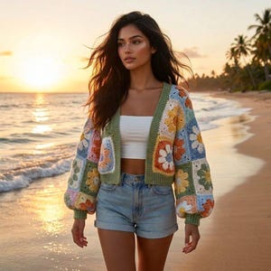 Peut inclure: Un cardigan en crochet coloré avec des motifs floraux jaunes, oranges, bleus et verts. Le cardigan a une bordure verte et est porté avec un haut blanc et un short en jean. L'image est prise sur une plage au coucher du soleil.