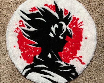 May include: A white circular rug with a black silhouette of a character with spiky hair in front of a red sun. The rug is made of fluffy material.