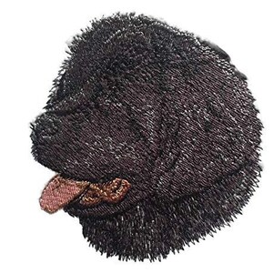 May include: Embroidered patch of a black dog with a pink tongue. The dog is facing left and has a fluffy, furry appearance.