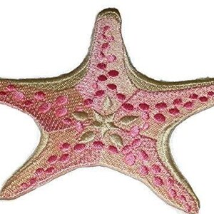 Puede incluir: Un parche bordado de estrella de mar rosa y dorado. La estrella de mar tiene un diseño detallado con puntadas rosas y doradas.