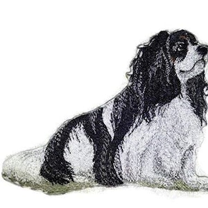 May include: Black and white embroidered patch of a Cavalier King Charles Spaniel dog sitting with its head turned to the side.