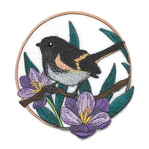 Peut inclure: Patch brodé représentant un oiseau noir et blanc avec des accents orange perché sur une branche avec des fleurs violettes. L'oiseau est entouré de feuilles vertes et le motif est placé dans un cadre circulaire.