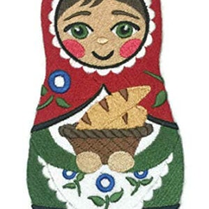 Könnte beinhalten: Gestickte Filz-Nistpuppe mit rotem, grünem und blauem Design. Die Puppe hält einen Korb mit Brot.