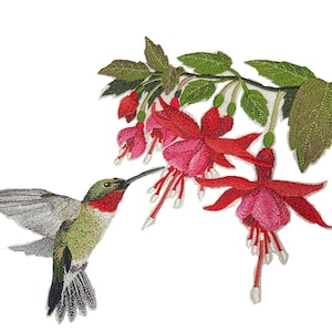 May include: An embroidered patch featuring a hummingbird with green, red, and grey plumage hovering near a branch of vibrant pink and red fuchsia flowers with green leaves. The detailed stitching captures the bird's wings and the floral textures.