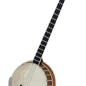 May include: An embroidered patch shaped like a five-string banjo. The instrument features a round cream-coloured head, a brown wooden rim with silver accents, a long neck with a black fretboard, and a brown headstock with four white tuning pegs.
