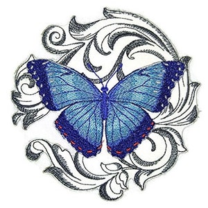 Puede incluir: Una mariposa azul con detalles negros y rojos está bordada sobre un fondo blanco con un diseño floral decorativo.