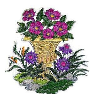 Puede incluir: Parche bordado con un arreglo floral en una urna decorativa. Las flores son rosas y moradas, y la urna es dorada. El parche está rodeado de follaje verde.