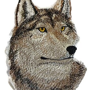 Op de afbeelding: Gestikte patch van een wolfskop met bruin en grijs bont, een scherpe zwarte neus en gele ogen.