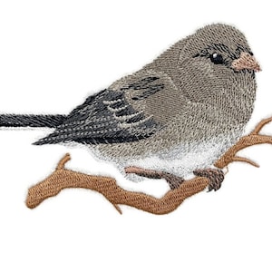 May include: Embroidered patch of a gray and white bird perched on a brown branch. The bird has a dark gray wing and a white belly.