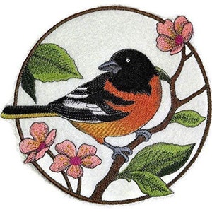 Peut inclure: Patch brodé représentant un oiseau coloré perché sur une branche avec des fleurs roses. L'oiseau a des plumes noires, blanches, orange et jaunes. L'arrière-plan est un cercle blanc avec une bordure brune.