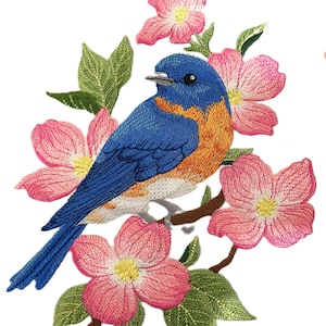 May include: Embroidered patch featuring a bluebird perched on a branch with pink blossoms. The bird has a blue body, orange breast, and a black eye. The flowers have yellow centers and green leaves.