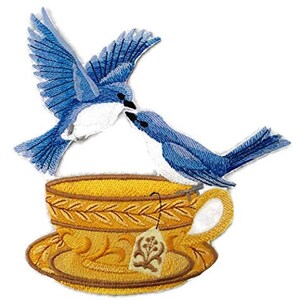 May include: Embroidered patch featuring two bluebirds perched on a yellow teacup and saucer. The birds are facing each other and appear to be sharing a cup of tea. The teacup has a floral design and a tea bag tag.