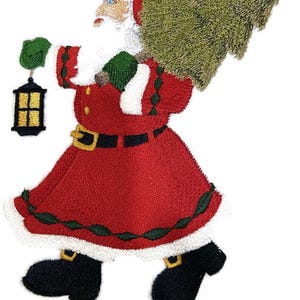 May include: Embroidered Santa Claus figure in a red suit with white trim, carrying a green Christmas tree and a black lantern. The Santa figure has a white beard, blue eyes, and a black belt with a gold buckle. The figure is wearing black boots with gold buckles.
