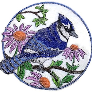 Può includere: Un toppa ricamata da stirare con un ghiandaia azzurra appollaiata su un ramo con fiori rosa e bianchi. L'uccello ha un corpo blu, un petto bianco e occhi neri. La toppa è circolare e ha uno sfondo bianco.