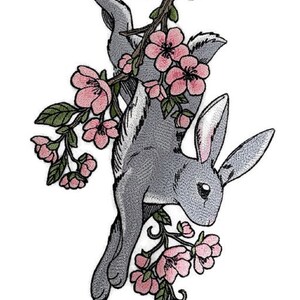 May include: A gray rabbit with long ears is hanging from a branch of a tree with pink blossoms. The rabbit is facing to the right and its tail is curled up. The tree branch is covered in pink flowers and green leaves.