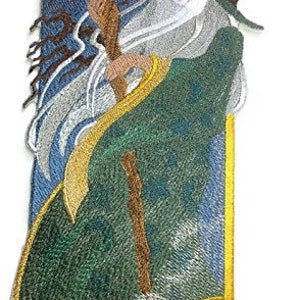 May include: Embroidered iron-on patch featuring a wizard with a long white beard and a pointed hat, holding a staff with a glowing orb at the top. The wizard is standing in front of a blue and green background with clouds and stars.