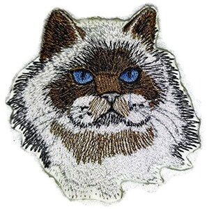 Puede incluir: Parche bordado de un gato blanco y marrón con ojos azules. El gato tiene un pelaje largo y esponjoso y mira directamente al espectador.