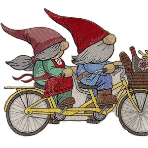 Peut inclure: Une broderie représentant deux gnomes sur un tandem jaune. Les gnomes portent des chapeaux rouges, et l'un a une veste verte et un tablier rouge. Le panier du vélo contient des fleurs, une bouteille et une baguette. L'image est sur fond blanc.