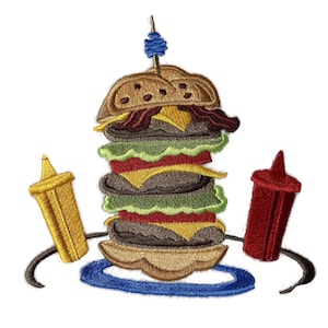 Pode incluir: Etiqueta bordada de um hambúrguer grande de vários andares com alface, tomate, queijo e picles. O hambúrguer está num prato com uma borda azul. Há duas garrafas de condimentos, uma amarela e uma vermelha, de cada lado do prato.