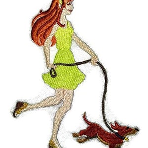 May include: Embroidered patch featuring a woman in a lime green dress walking a red dachshund on a black leash. The woman has long red hair and is wearing gold shoes. The patch is on a white background.
