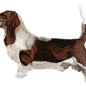 Könnte beinhalten: Gestickter Aufnäher eines braunen und weißen Basset Hundes mit einem langen, schlaffen Schwanz.