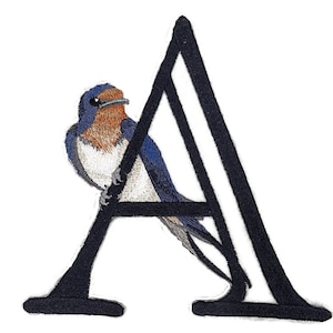 May include: A black embroidered letter A with a blue and white swallow perched on the top of the letter.